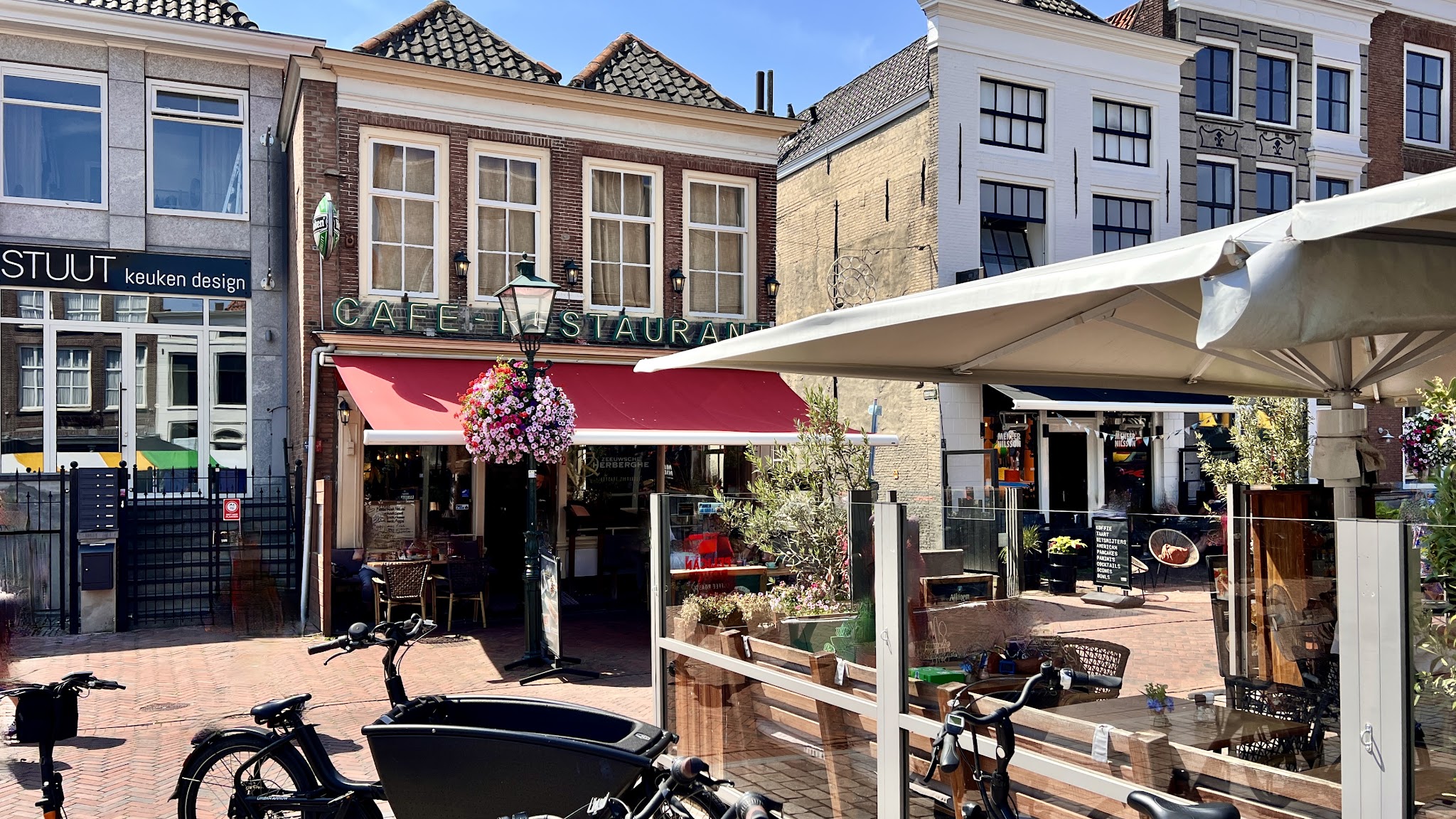 De gevel van De Zeeuwsche Herberghe met de rode luifel en het terras