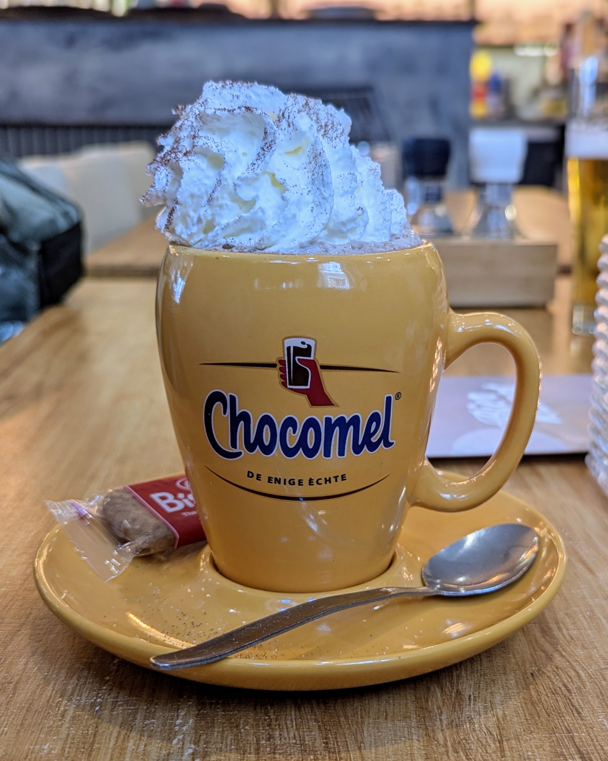 Warme chocolademelk met een toef slagroom in een gele mok